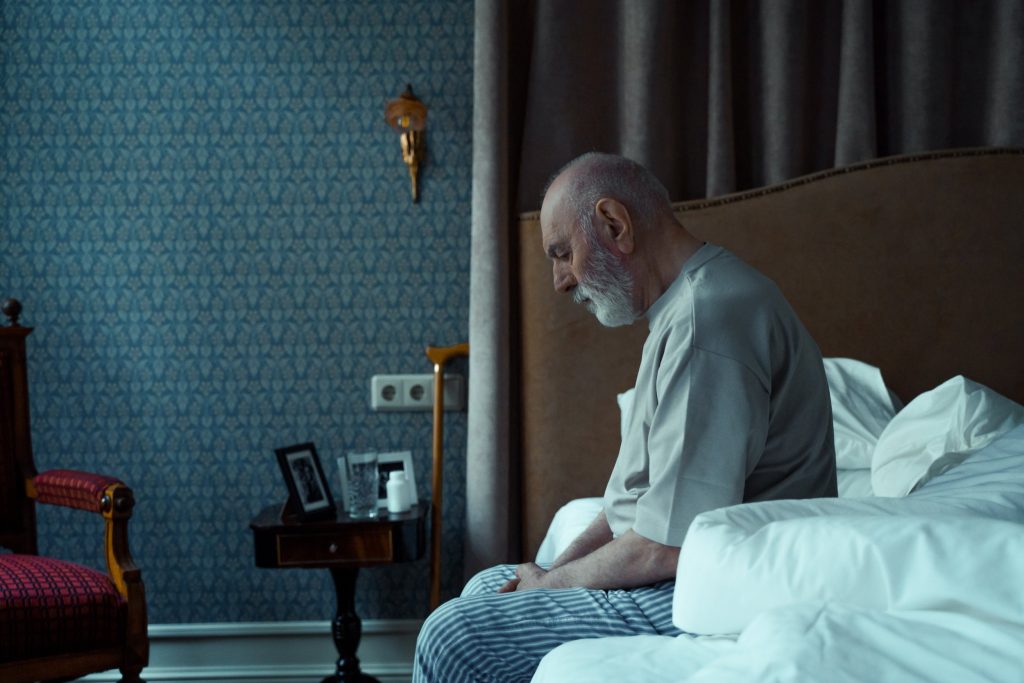 an elderly person sitting on his bed