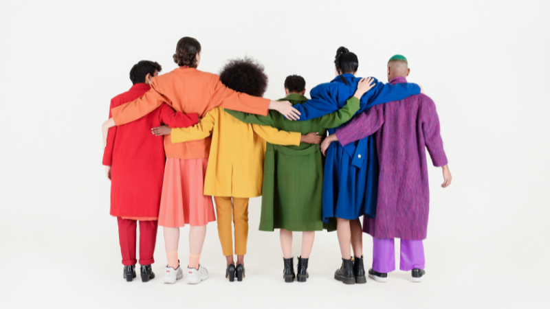 Group of people wearing colorful clothes holding each other